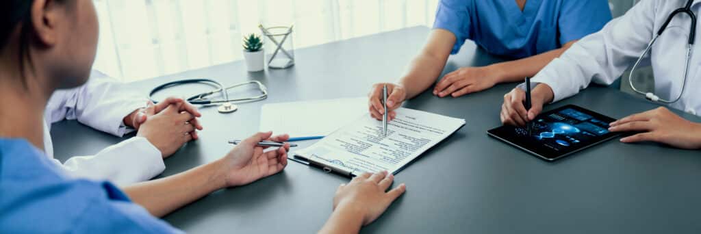 Doctors review wound care EHR data with a tablet at a desk.