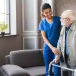 nurse at a SNF helps a patient in a walker